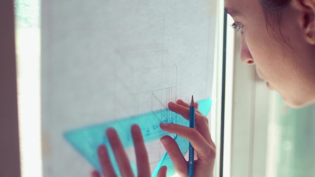 Teen girl tracing lines on plan
