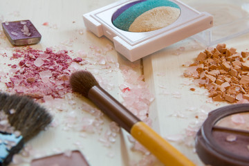 women's accessories cosmetics. Makeup brushes and crushed eyeshadow on wooden background