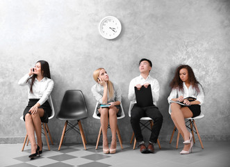 Young people sitting on a chairs in grey hall