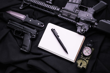 Weapon, notebook, pen, knife and compass on black fabric/Notebook, pen, knife, assault rifle and compass on black cloth,top view
