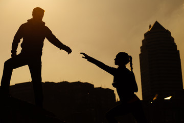 Silhouette picture of man helping a woman climb