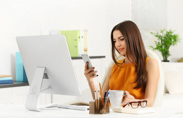 A beautiful successful woman with mobile phone sitting at the modern office