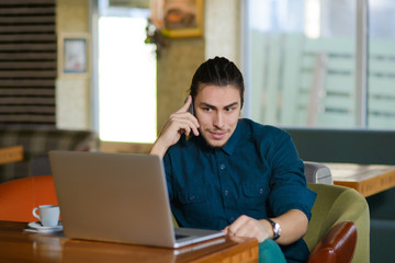 Young man drinking coffee and working on laptop in a cafe