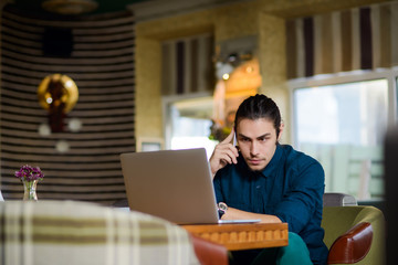 Young man drinking coffee and working on laptop in a cafe