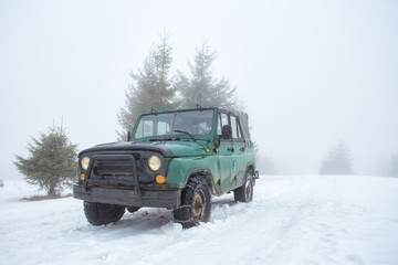Green off-road vehicle on the snow-covered mountain