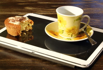 Tablet usato come vassoio, con tazzina di caffè e pasticcino