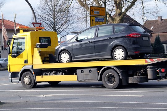 Gelber Abschleppwagen transportiert einen PKW
