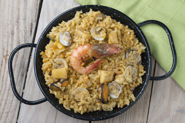 Vegetable paella with seafood on a wooden background