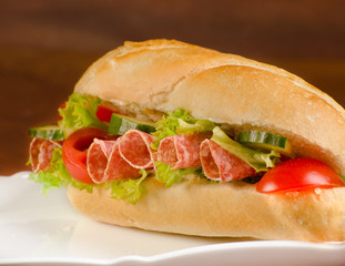 baguette, submarine sandwich, topped with salami, cucumber and t