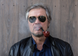 man smokes a pipe in glasses