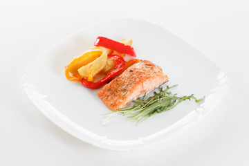 Grilled salmon fillet with vegetables, spices and arugula on a plate
