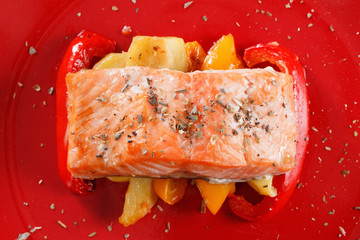Grilled salmon fillet with vegetables, spices and arugula on a plate