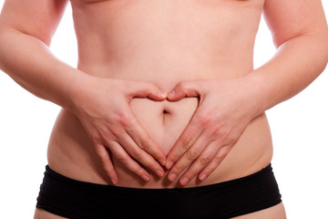 Frau hat Herzform aus den Händen auf ihren Bauch gemacht