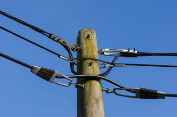 wooden electricity post against blue sky