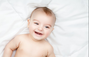 Cute and funny little baby smiling over white blanket. Copy spac