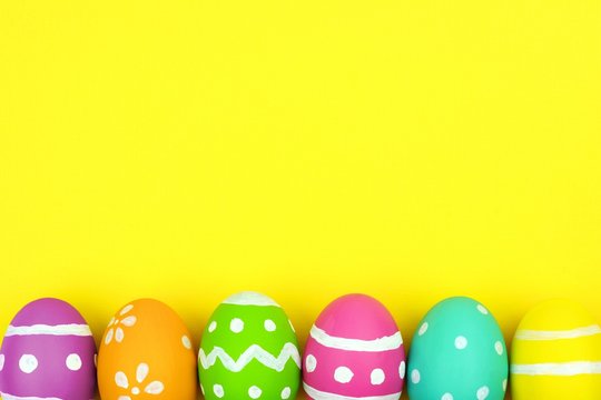 Colorful Easter egg bottom border over a yellow paper background