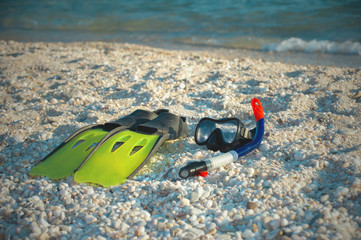 Mask, snorkel and fins for snorkeling on a sandy beach.