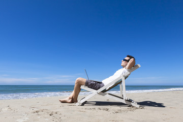 Freelancer resting on sunny tropical beach with sunglasses