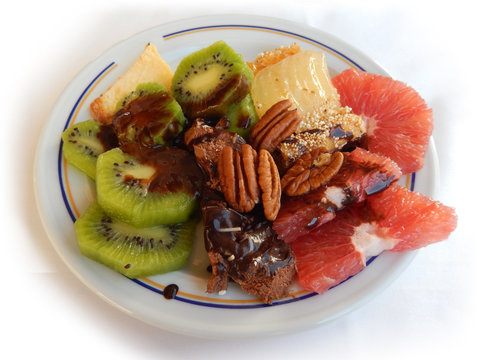 Breakfast plate with sweet desserts, chocolate syrup, nuts, fresh kiwi, mango and grapefruit slices, at an all-inclusive buffet