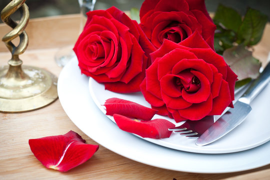 Table setting with red roses on plate - celebrating Valentine's