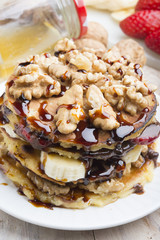 Pancakes with banana , walnut & chocolate on wood background