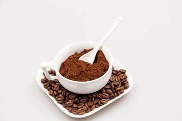 White coffee cup, coffee plate and teaspoon with coffee beans and coffee powder