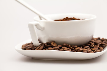 White coffee cup, coffee plate and teaspoon with coffee beans and coffee powder