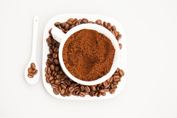 White coffee cup, coffee plate and teaspoon with coffee beans and coffee powder