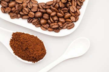 White coffee cup, coffee plate and teaspoon with coffee beans and coffee powder