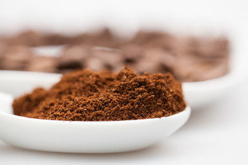White coffee cup, coffee plate and teaspoon with coffee beans and coffee powder