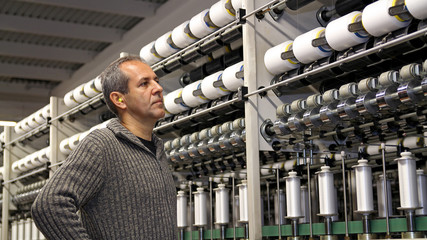 Engineer is Looking at the Machines in Textile Factory / Industrial Engineer Closely Monitor Every Step of the Yarn Manufacturing Process. - obrazy, fototapety, plakaty