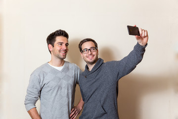 Zwei M&auml;nner machen ein fr&ouml;hliches Selbstportrait mit einem Smartphone 