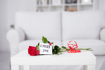 Red roses on table with note I miss you