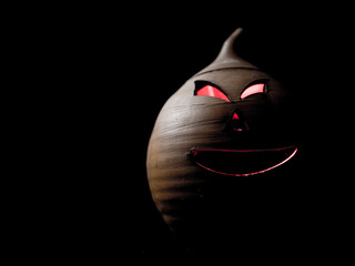 Clay lantern with orifices that resemble a face and red light coming out