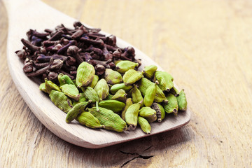 cardamom pods and cloves on wooden spoon