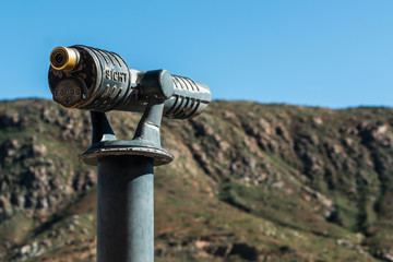 Sightseeing binoculars pointed at top mountain range. 