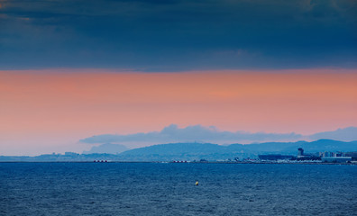 Fototapeta premium France, Nice, 2015.09.12: International airport at the sunset, mediterranean sea, lights arriving and departing aircraft, pink sky