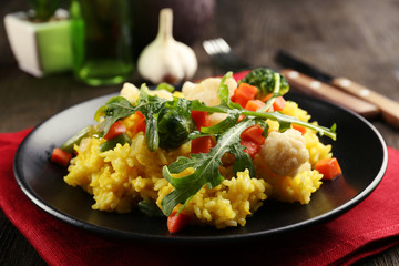 Black plate with vegetable risotto on served wooden table