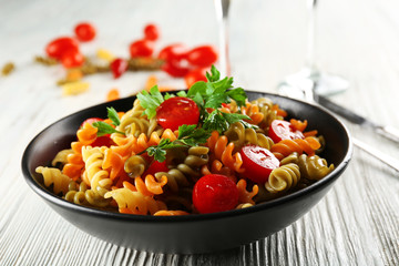 Delicious macaroni dish in black bowl on served grey wooden table