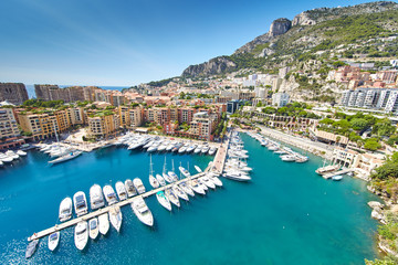 Obraz premium Monaco, Fontvieille, 29.08.2015: Port Fontvieille, panorama, widok z góry z Monaco Ville, lazurowa woda, refleksy słońca na wodzie, port, słoneczny dzień, luksusowe apartamenty, jachty, skały