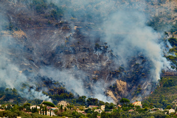 Italy, Ventimiglia, 2015.09.09: Fire in the forest mountain in the Italian town of Ventimiglia, all the mountains in the smoke, the villa is on fire, the fire service aircraft extinguish a fire