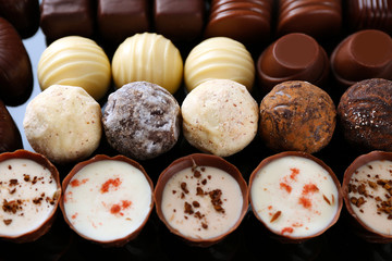 Assorted chocolate candies on black background, close up