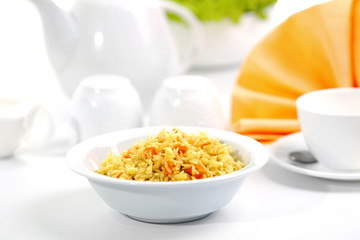 Stewed rice with a carrot in a white bowl on a table