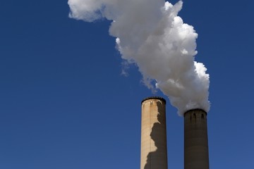 White smoke coming out of power plant chimneys on blue sky background