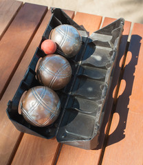 Metallic petanque balls and a small red jack on wood table