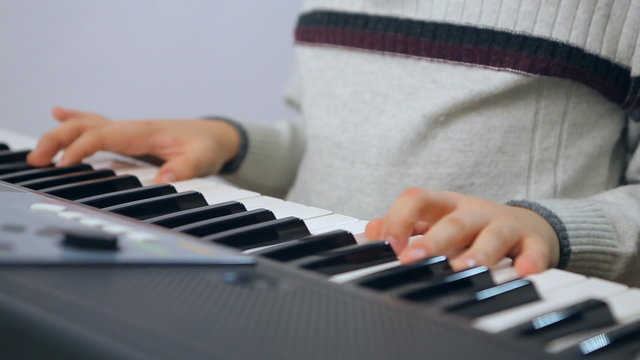 Child boy teen keyboardist playing on an electronic keyboard instrument. Gifted kid
