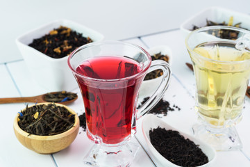 Assortment of dry tea and glass cup with green tea and red tea.