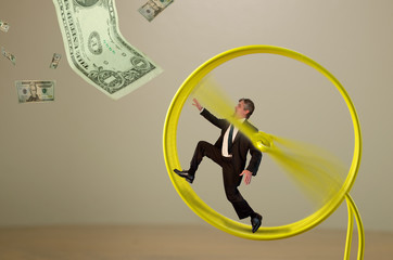 A businessman is running on a hamster wheel fruitlessly chasing a dollar bill hanging just outside his reach representing many financial business concepts - 102280481