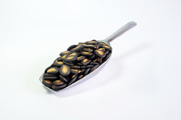 Watermelon seeds in aluminium spoon on white background