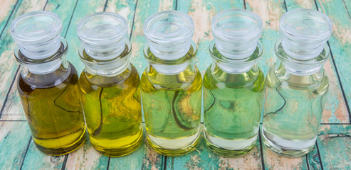 Avocado fruit oil, sesame seed oil, olive oil, grape seed oil and corn oil in vial glass bottle over rustic wooden background
